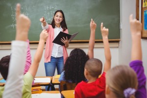 Teacher pointing to student, many students have hands raised